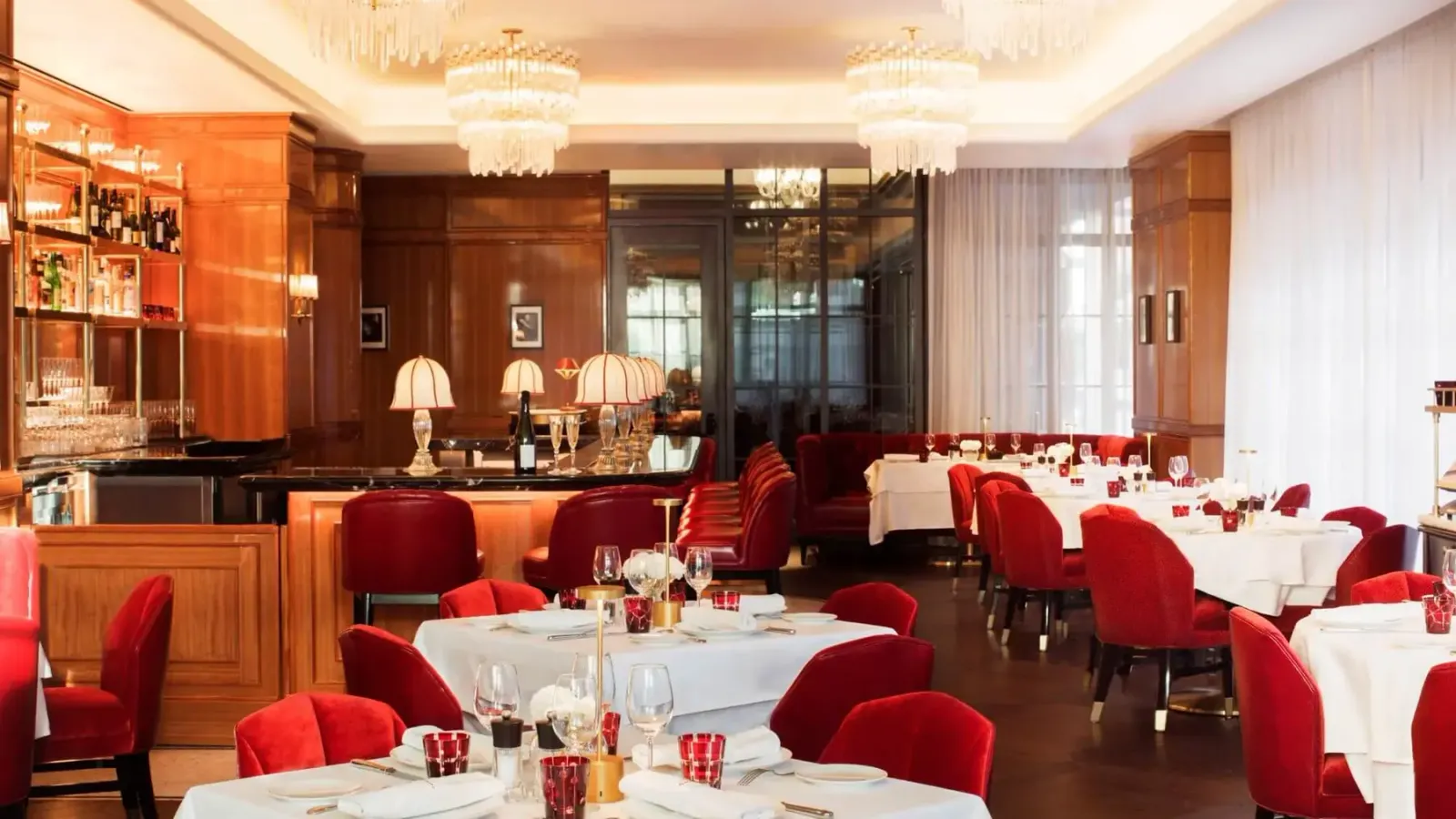 The red and cream dining room at Brasserie Fouquet's New York with crystal chandeliers and white tablecloths