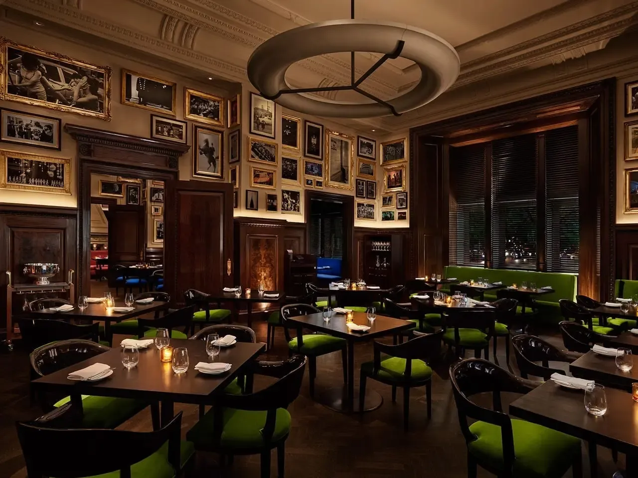 The Clocktower's green dining room with framed portraits, dark wood, and a sculptural ceiling light