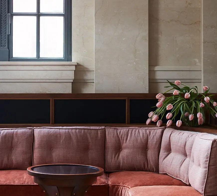 A curved rose velvet banquette beside the tall stone windows of Swan Room